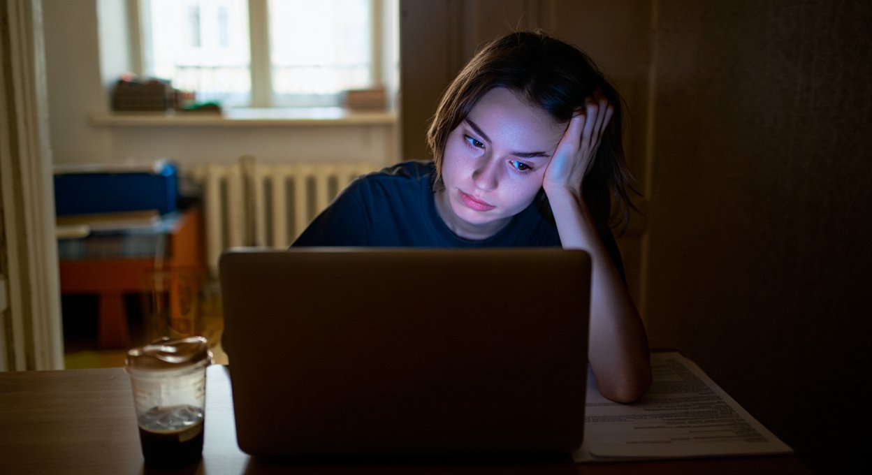 Девушка сидит в темноте за компьютером